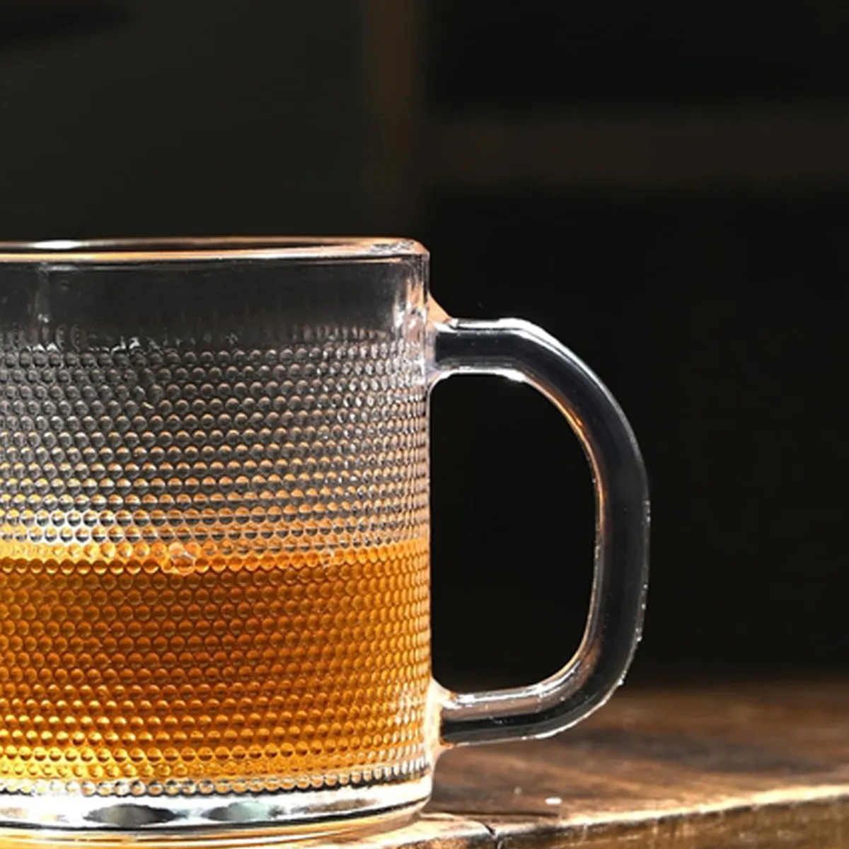 Close-up of a transparent textured glass mug filled with amber tea.