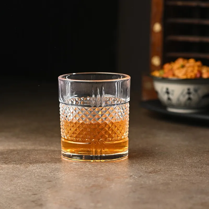 Single clear whiskey glass with geometric texture and amber drink
