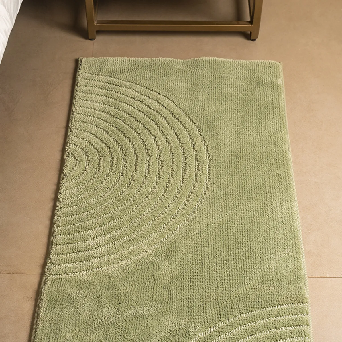 Green geometric runner rug shown beside a bed with concentric arc detailing