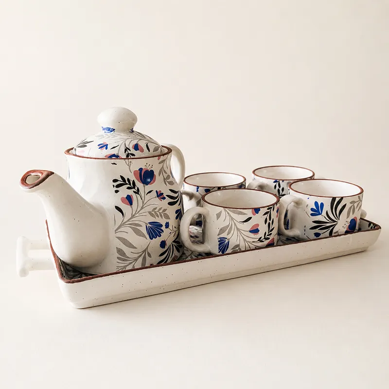 Blue and white floral ceramic tea pot with four cups on a tray