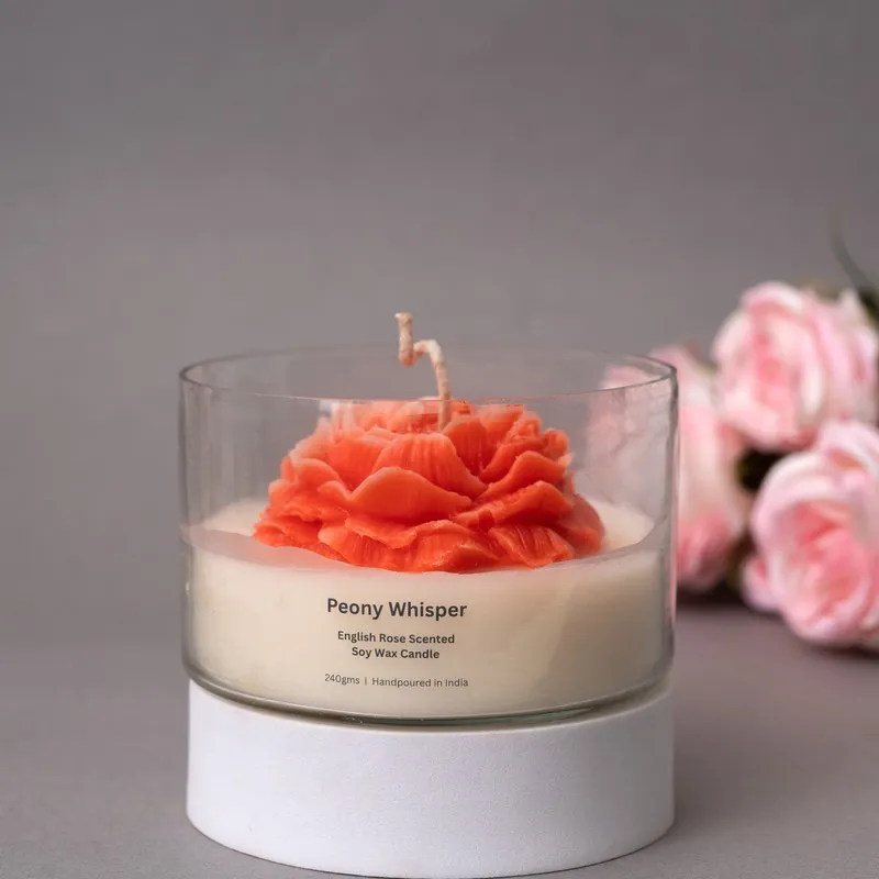 Close view of a red rose-shaped candle in a clear glass container