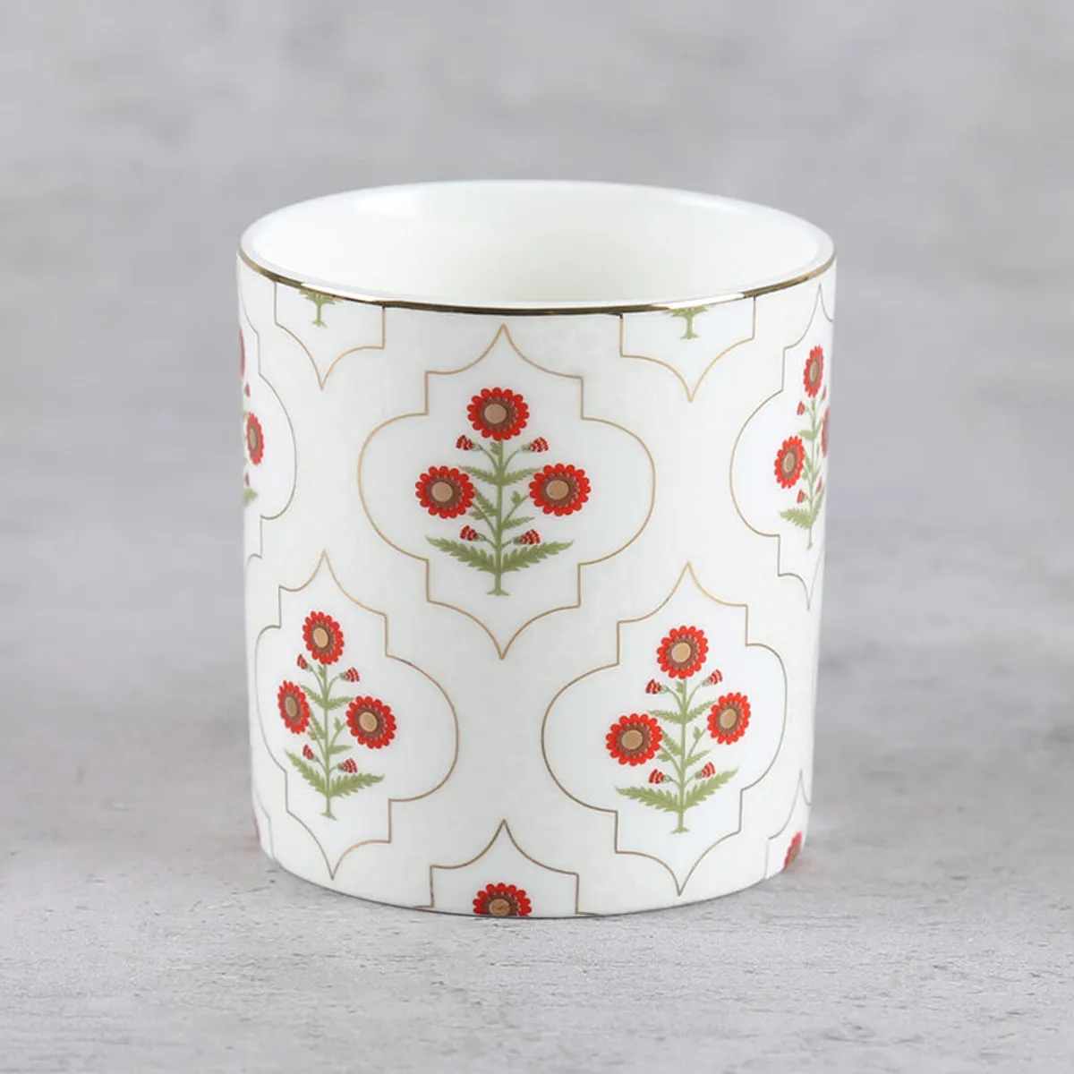 Front view of an ivory tea cup with repeating red floral and geometric motifs.