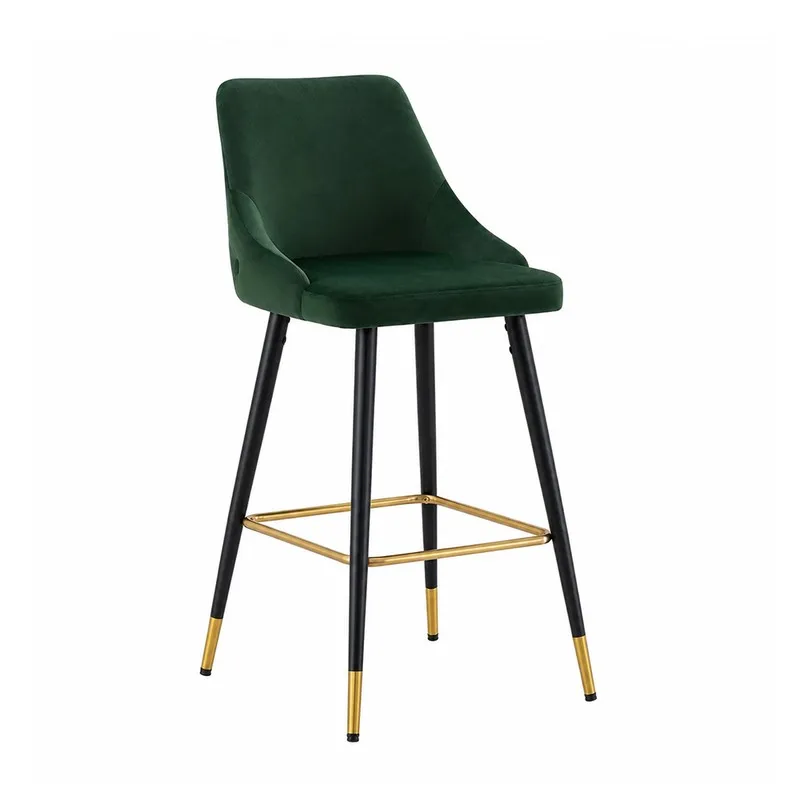 Angled view of a green velvet bar chair with black legs and gold accents