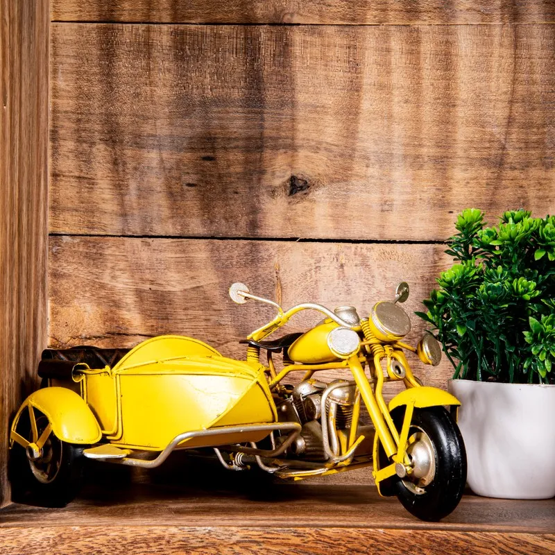 Yellow iron motorcycle with sidecar displayed on a wooden shelf