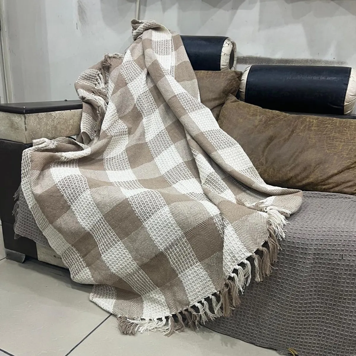 Beige and white throw casually draped over a sofa, showing its textured pattern and fringe