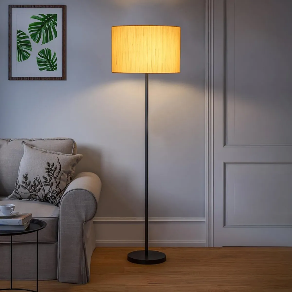 Lit ivory drum floor lamp beside a sofa in a softly lit room