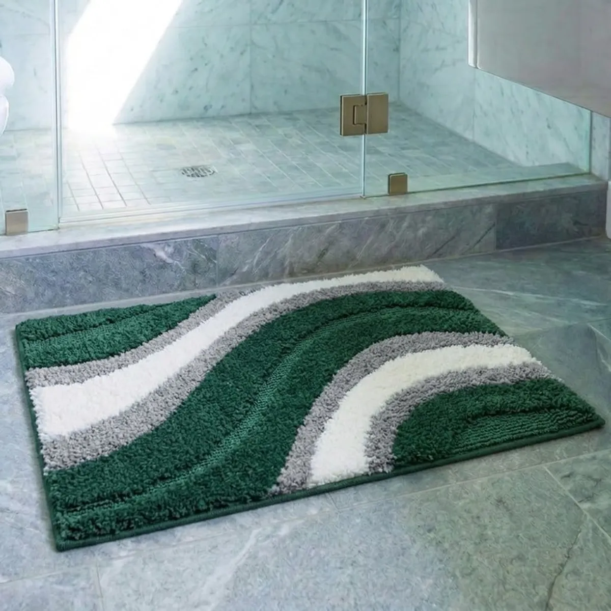 Green, grey and off-white wave-pattern bath mat placed beside a glass shower