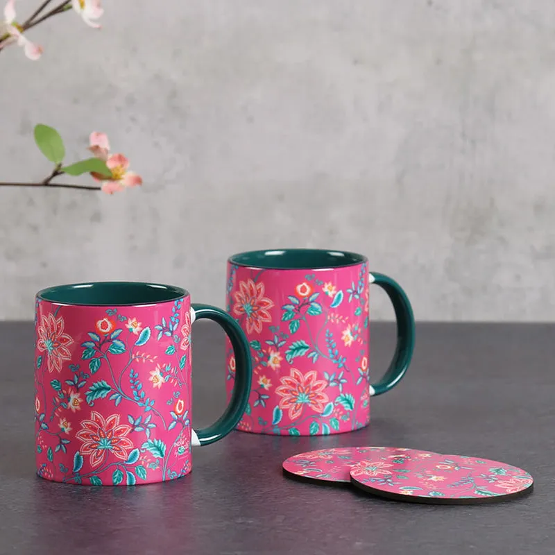 Two pink floral mugs with matching coasters on a tabletop
