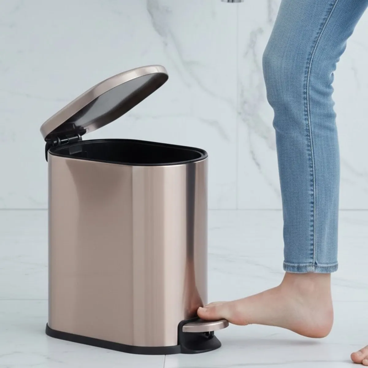 Gold metal pedal dustbin with lid open beside a foot pedal