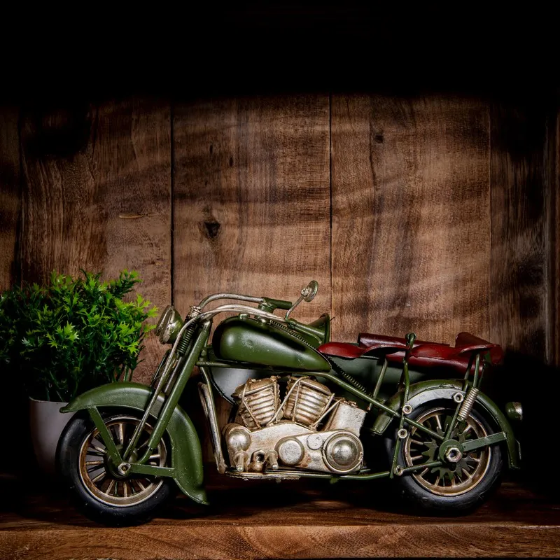 Side view of olive green vintage motorcycle showpiece with detailed metal body