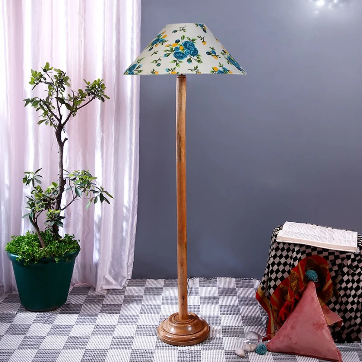 Floor lamp with white shade and blue blossom print beside a draped side table