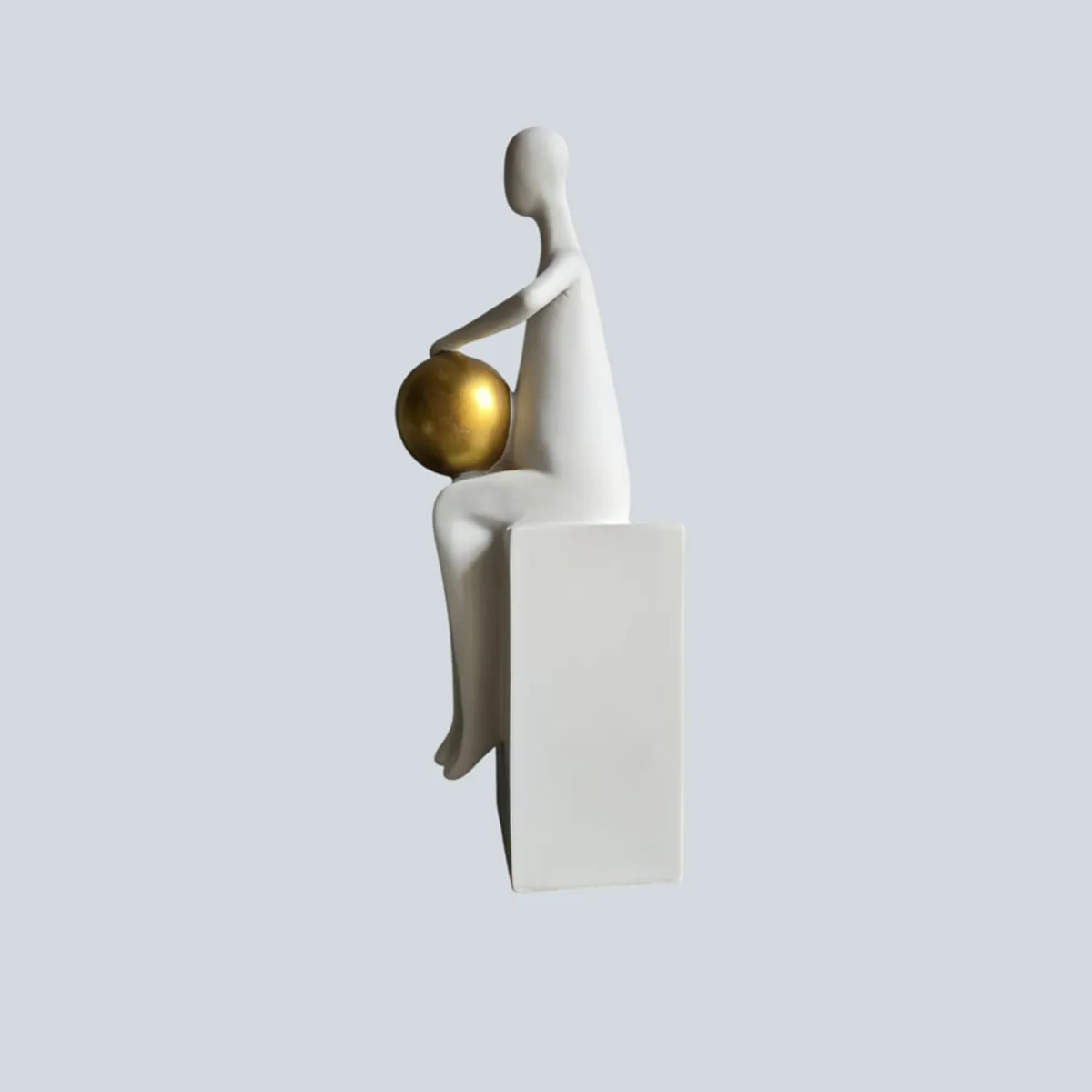 Side view of a white abstract figurine holding a gold sphere
