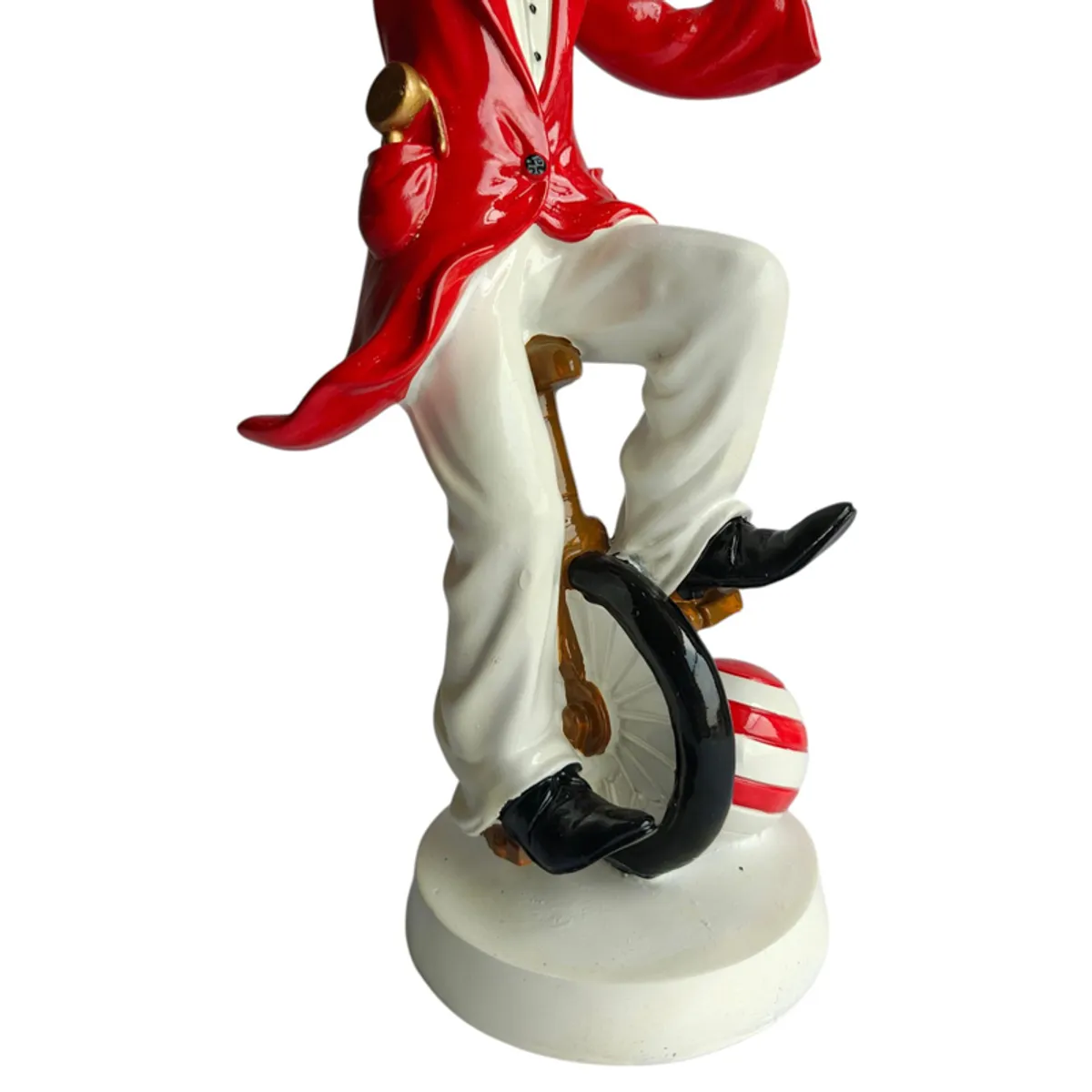 Close-up of the unicycle, white trousers and striped red ball