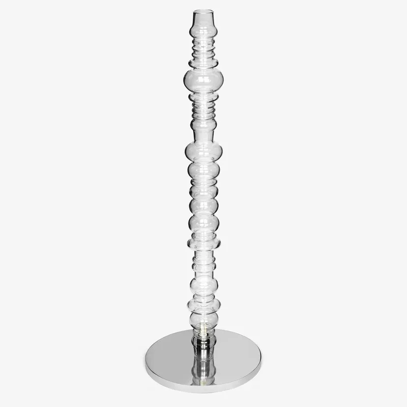 Angled view of transparent glass floor lamp on a round silver base