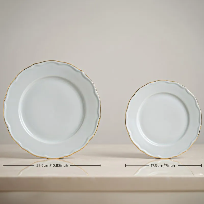 Large and small white plates with scalloped edges and gold rims