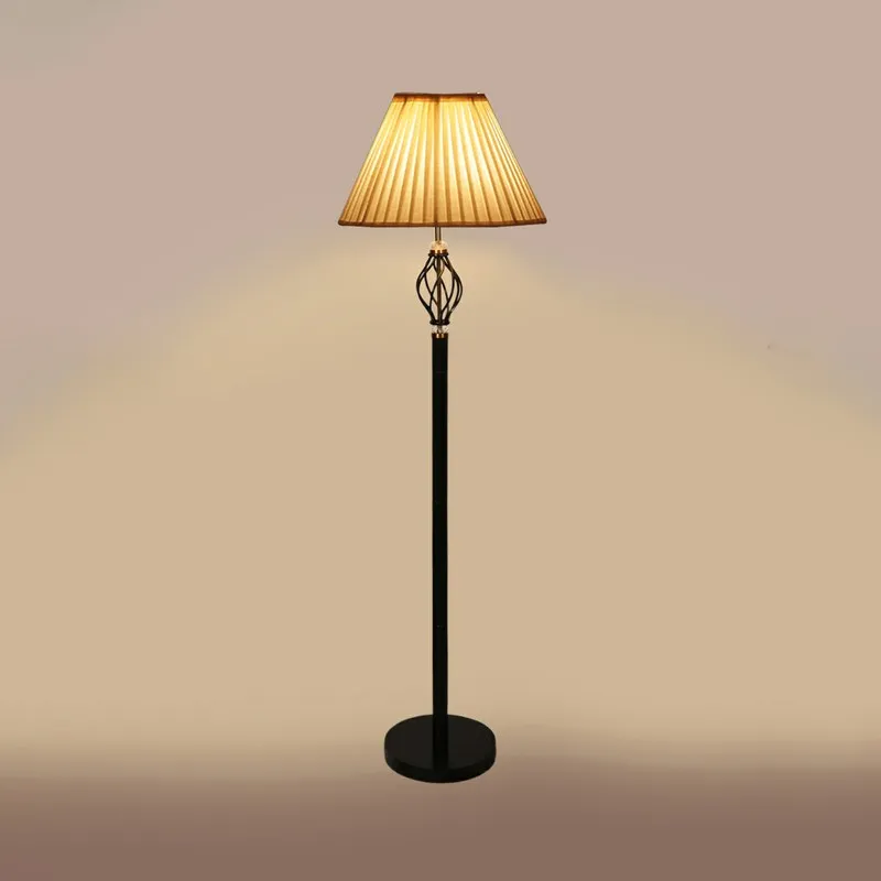 Lit black floor lamp with pleated shade against a plain warm beige background