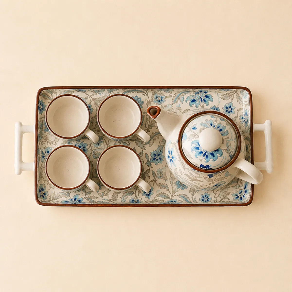 Top view of floral ceramic tea pot, four cups and rectangular tray