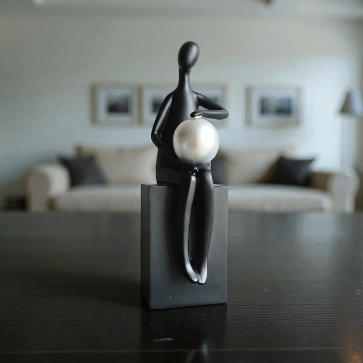 Black figurine with a silver sphere displayed on a dark tabletop