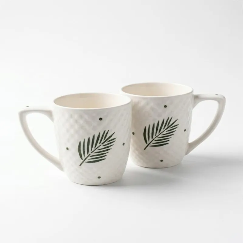 Pair of white ceramic leaf-print mugs shown against a plain background