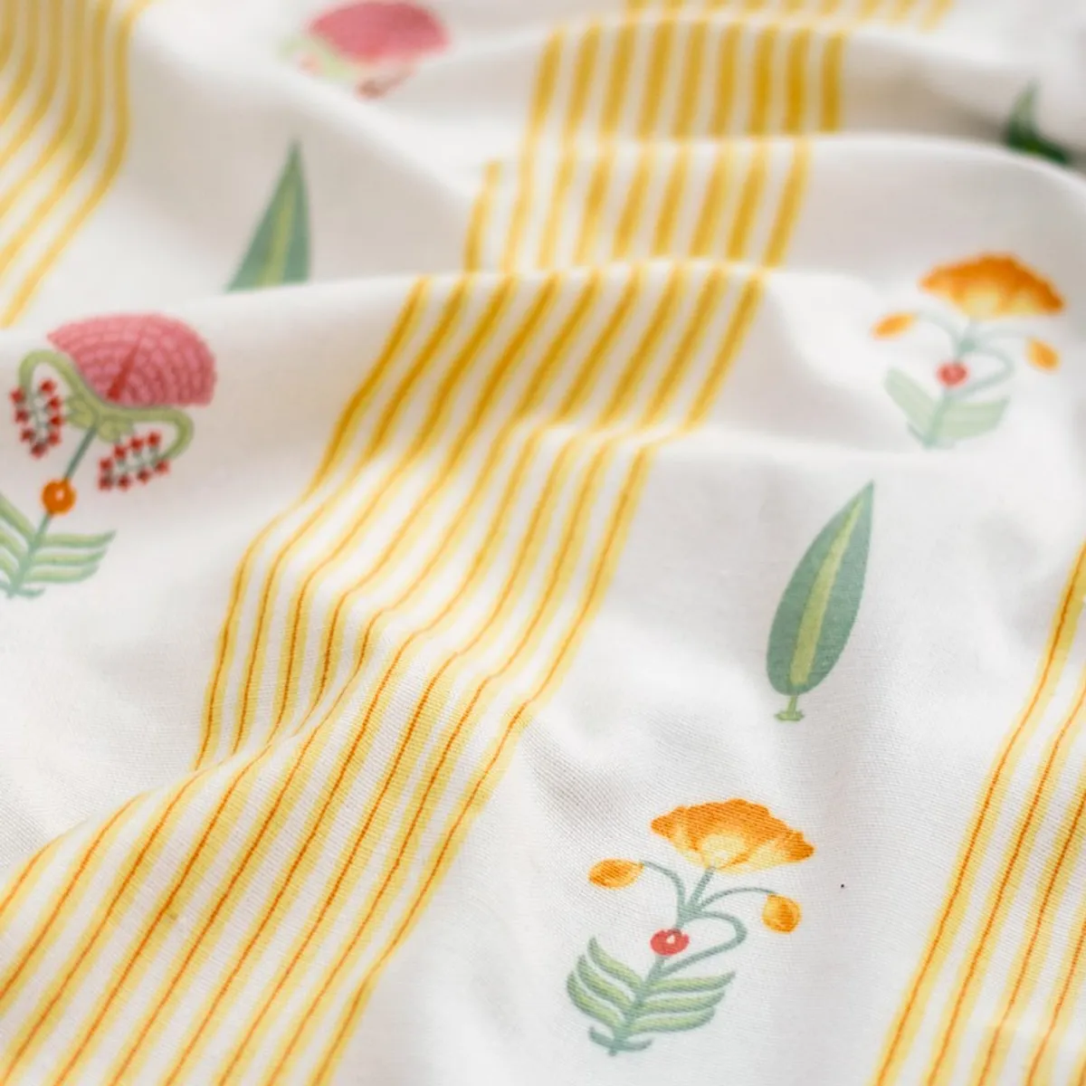 Close-up of cream curtain fabric with yellow stripes and colourful floral motifs