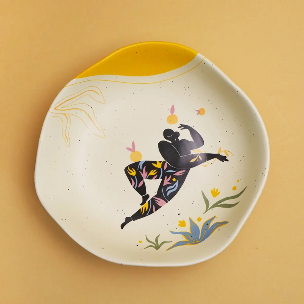 Top view of a cream plate with colourful figure, floral motifs and yellow accent