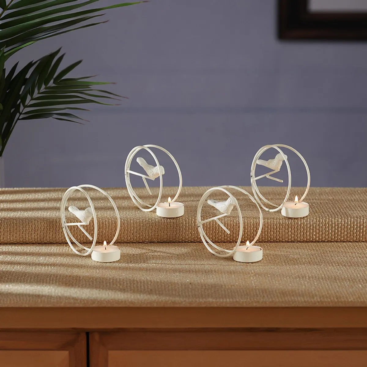 Four white bird-inspired tealight holders arranged on a textured surface
