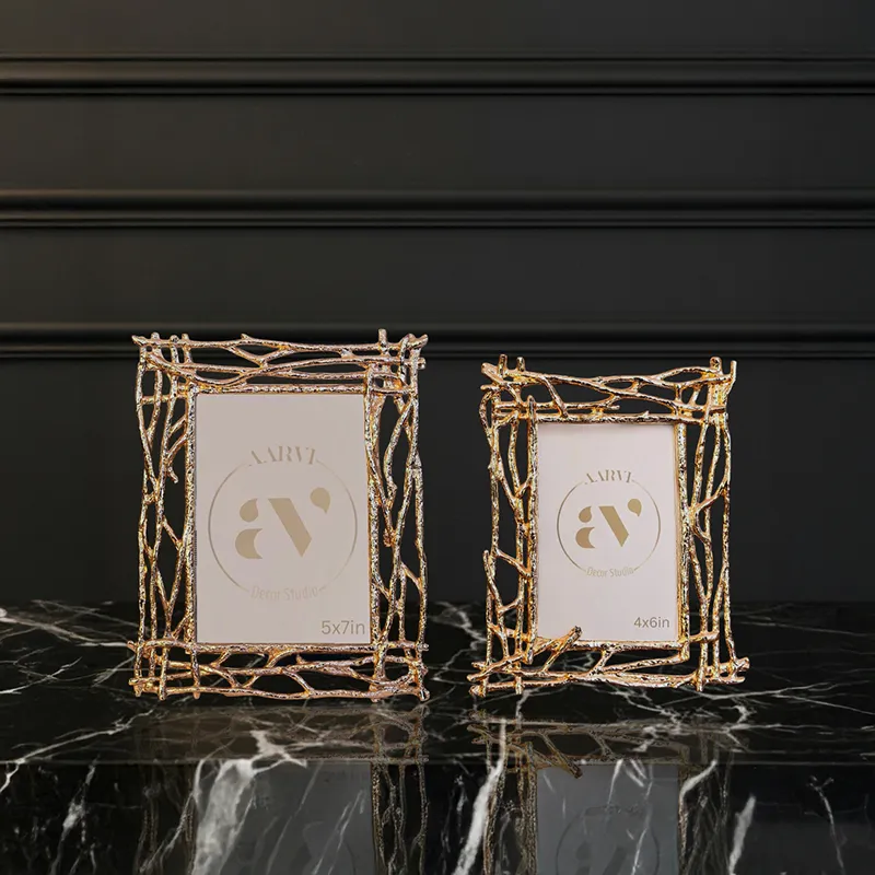 Two gold branch-style photo frames displayed together on a dark surface
