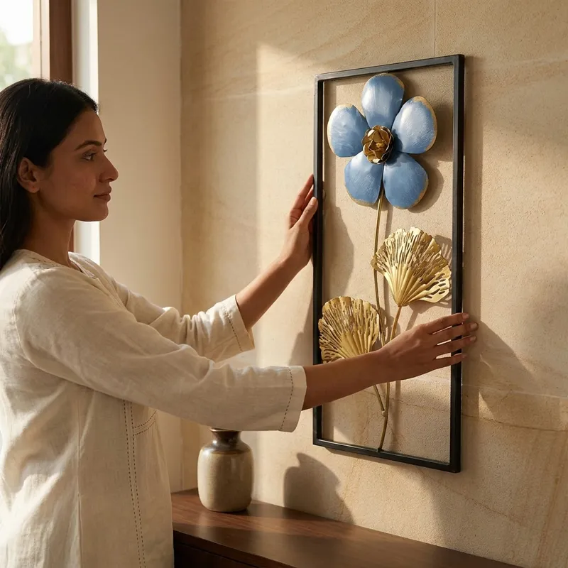 Rectangular metal wall accent with flower and foliage design being positioned on a wall