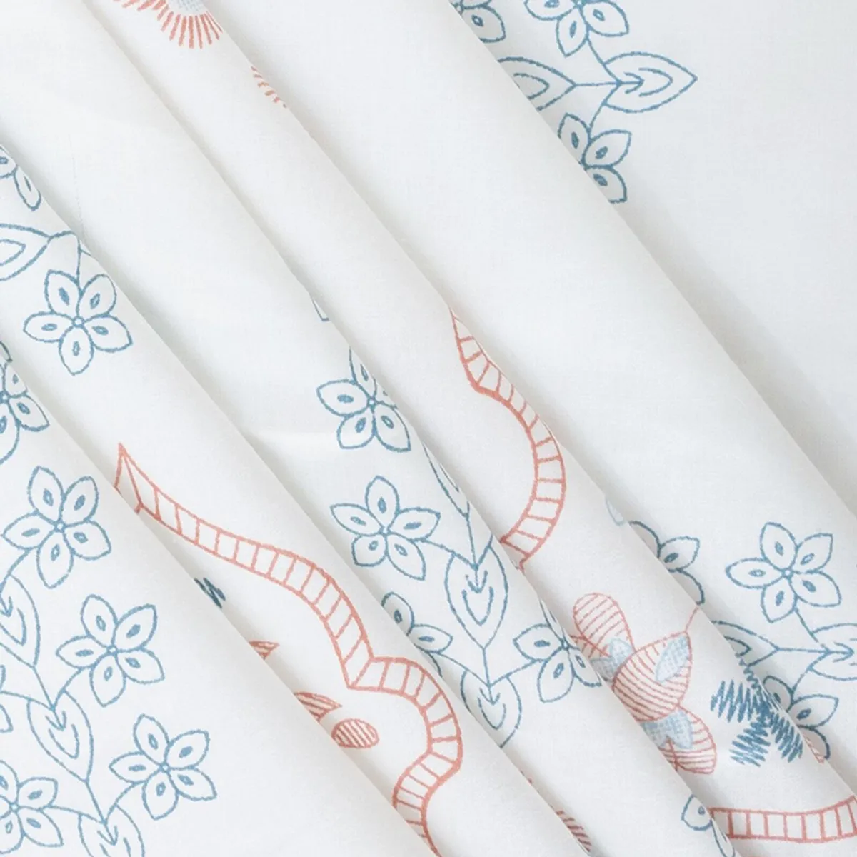 Draped white bedsheet showing blue flowers and coral botanical motifs