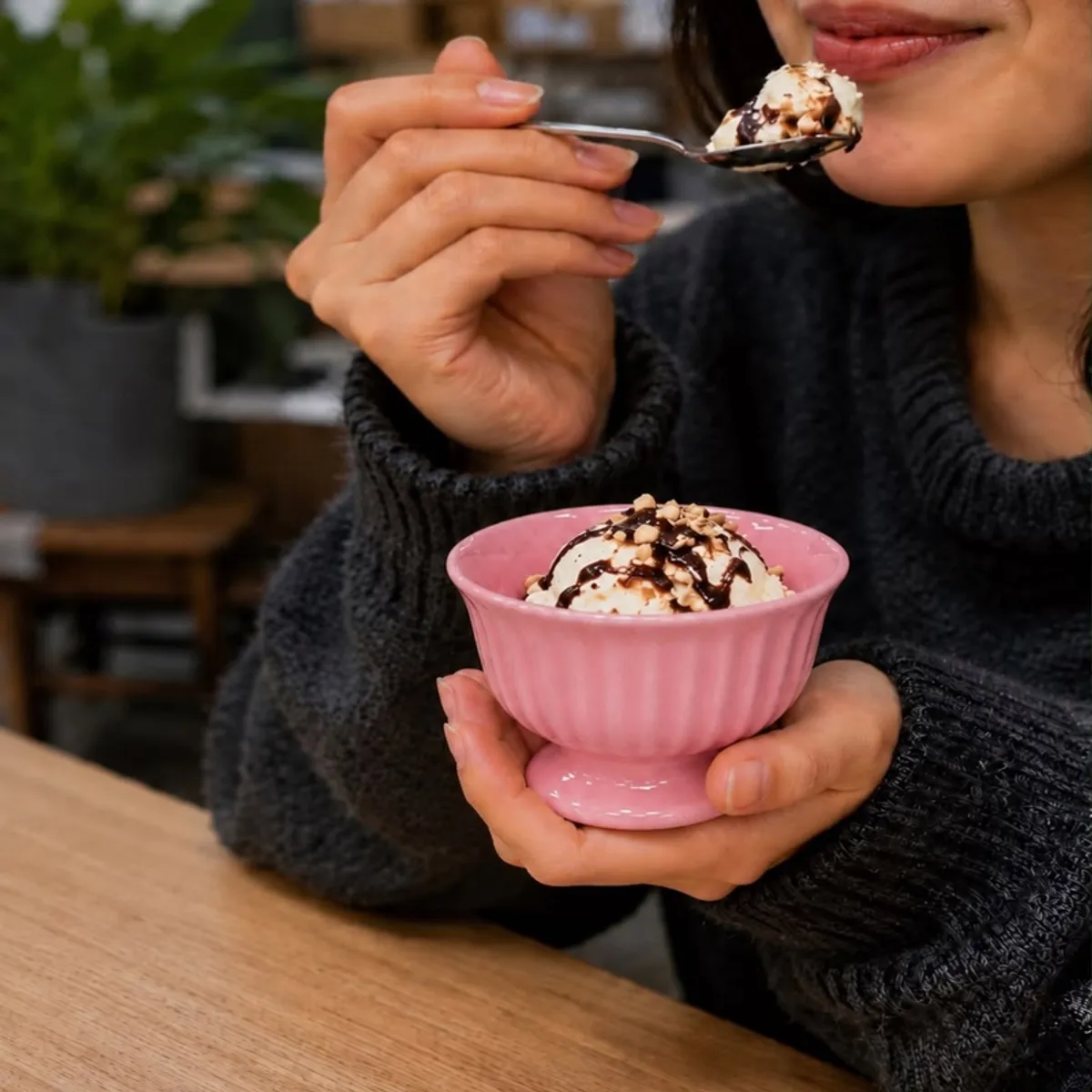 Person holding a pink dessert cup filled with ice cream