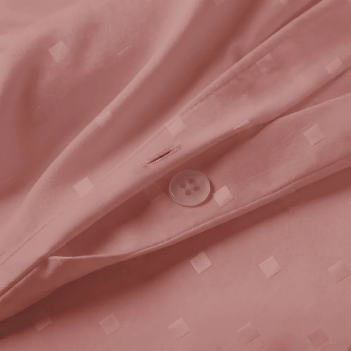 Close-up of rose-brown cotton duvet cover showing subtle square dot texture and button closure