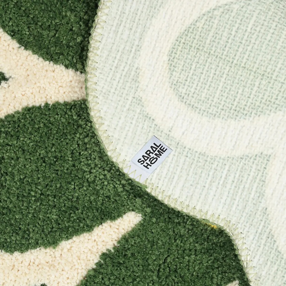 Underside of the green floral bath mat showing its pale backing and finished edge