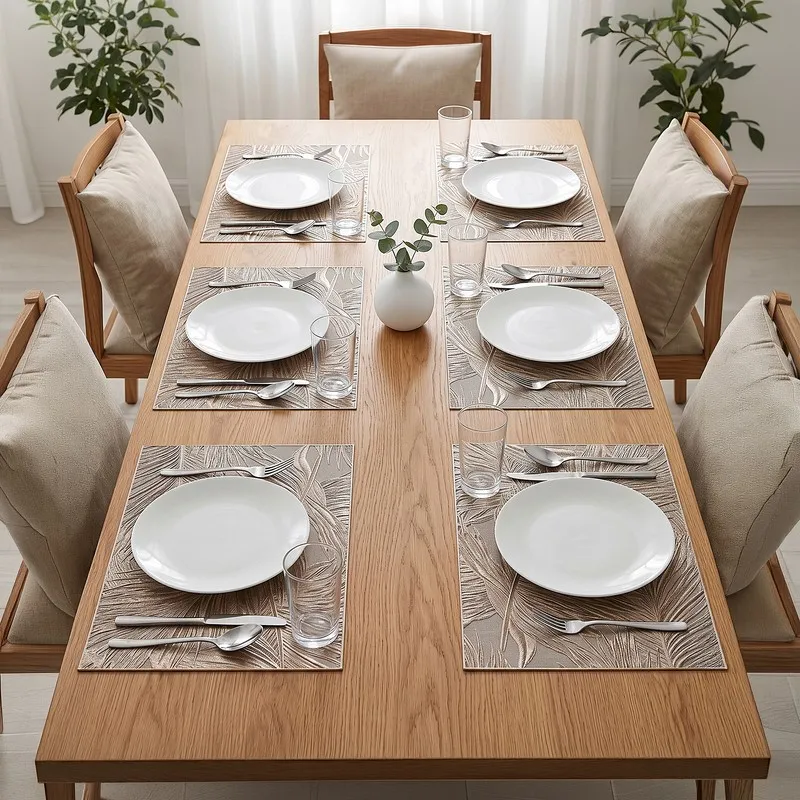 Six rectangular metallic palm leaf table mats arranged on a dining table with white plates