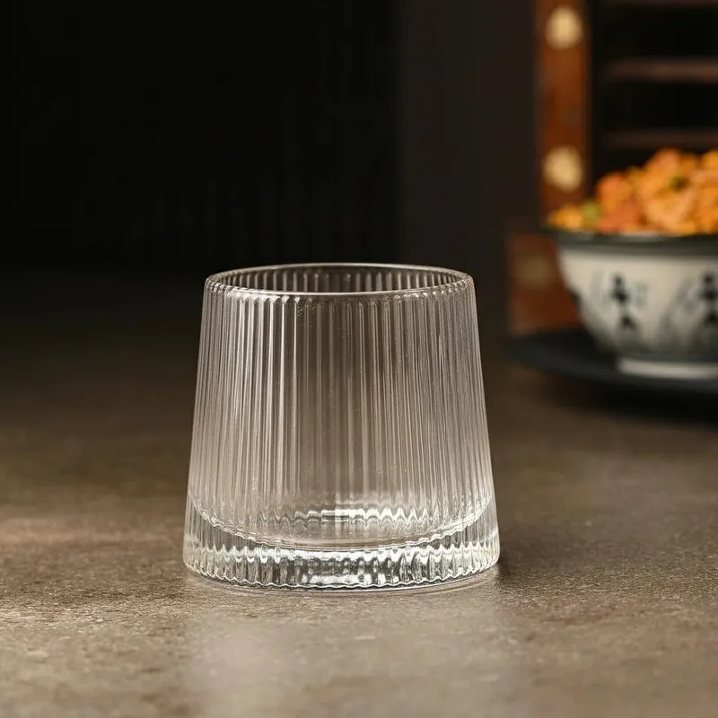 Single clear ribbed whiskey glass on a tabletop