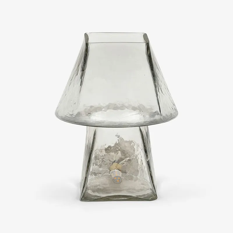 Front view of a clear glass table lamp with flared shade