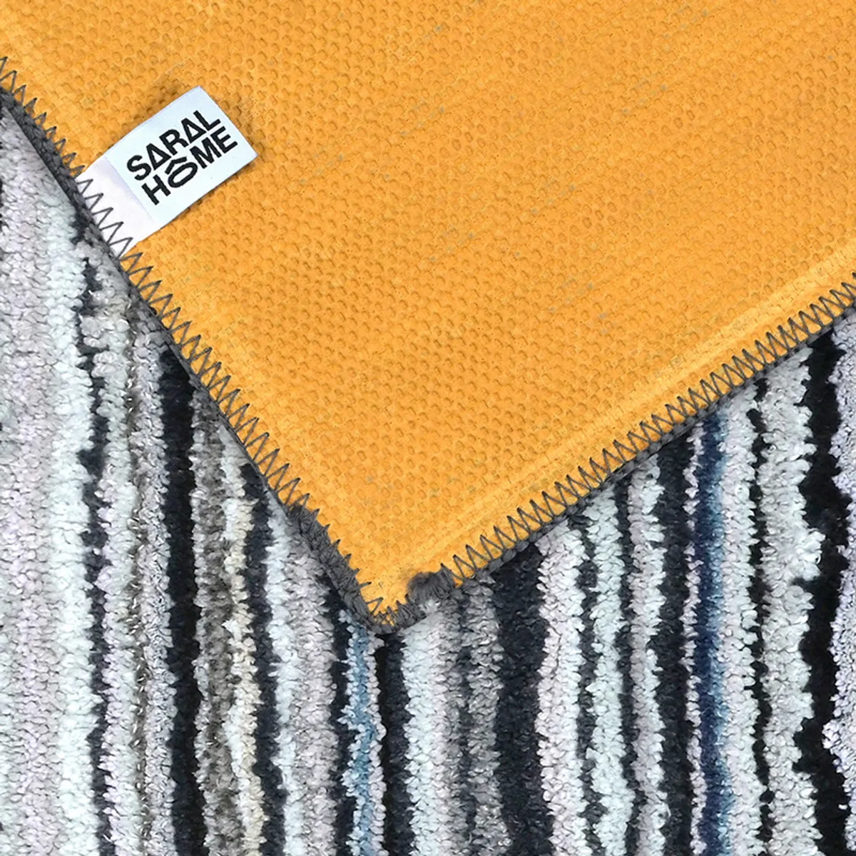 Underside of the carpet showing its orange anti-skid backing and stitched edge
