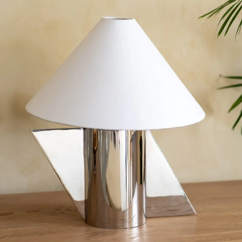 Close view of white cotton shade lamp with polished silver angular base