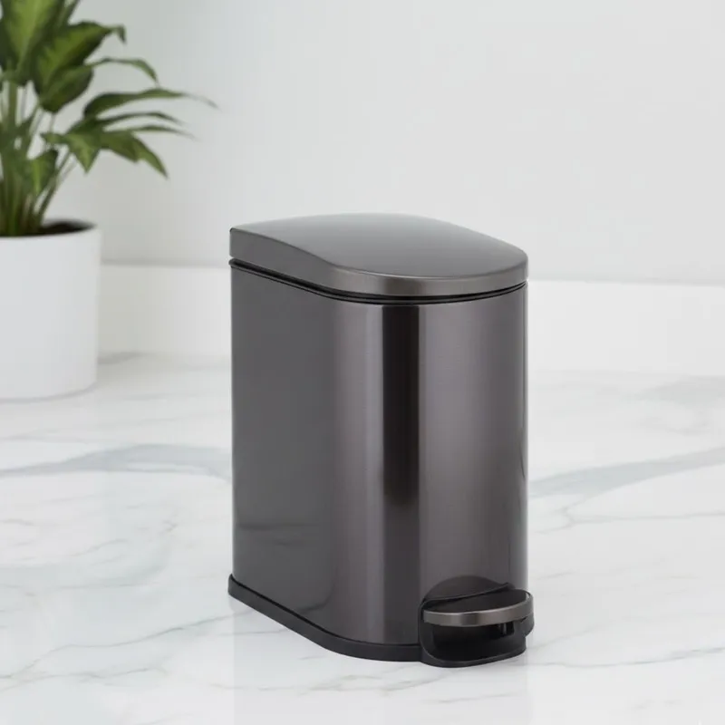 Black metal pedal dustbin with closed lid on a white surface