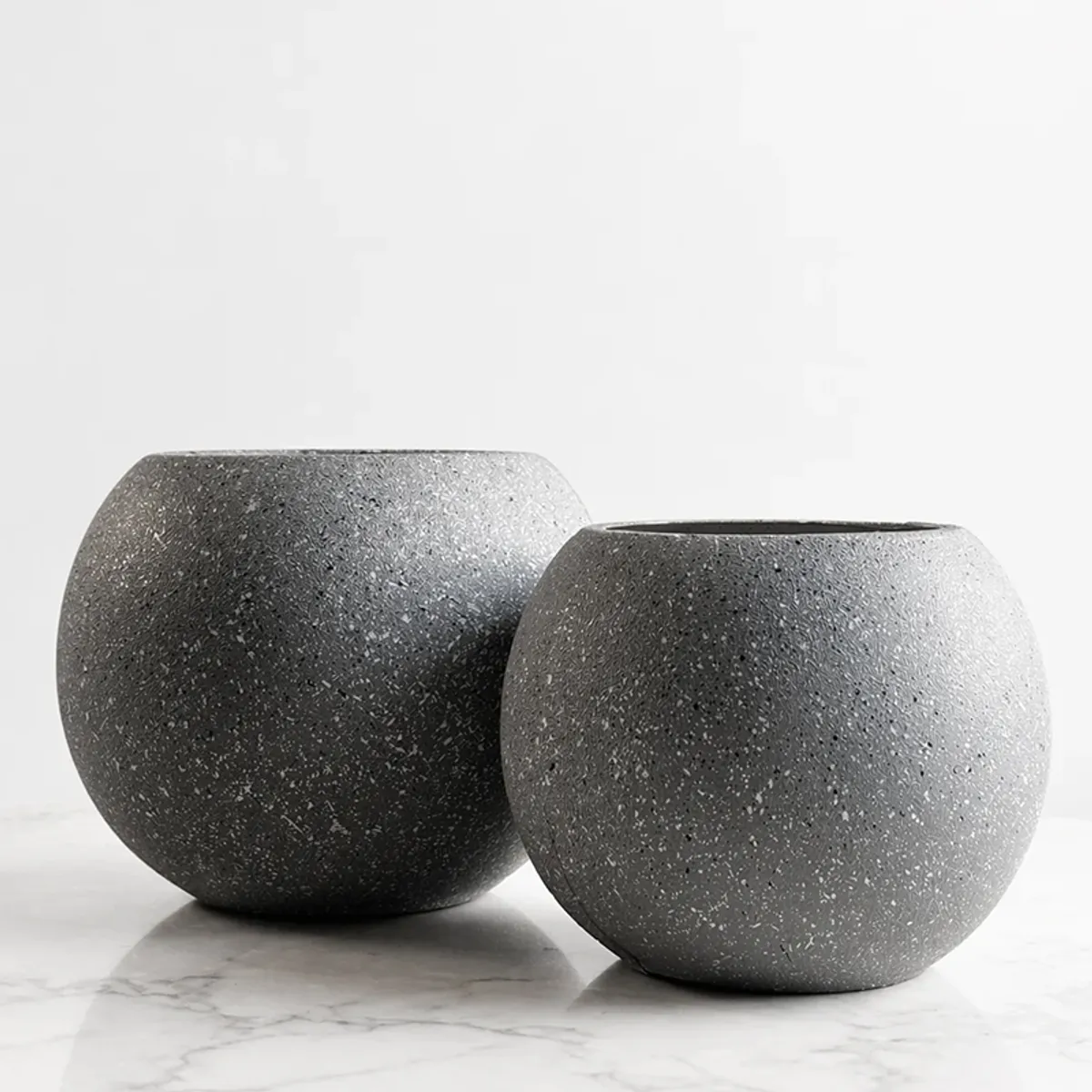 Two round grey speckled planters shown together against a white background