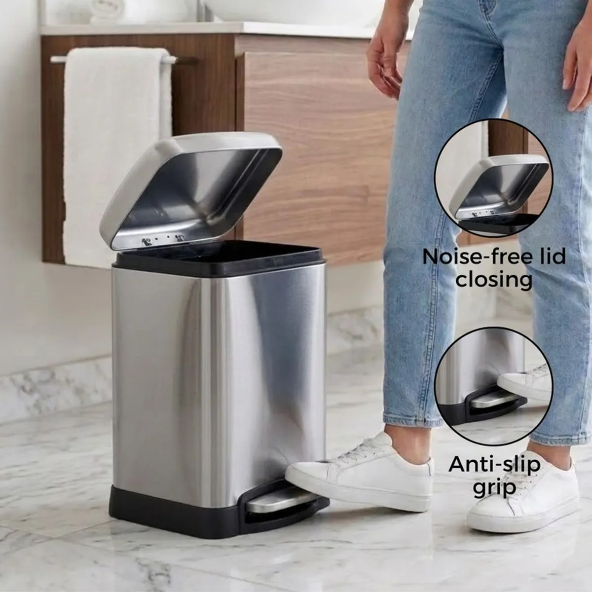 Silver pedal dustbin with lid open in a bathroom setting