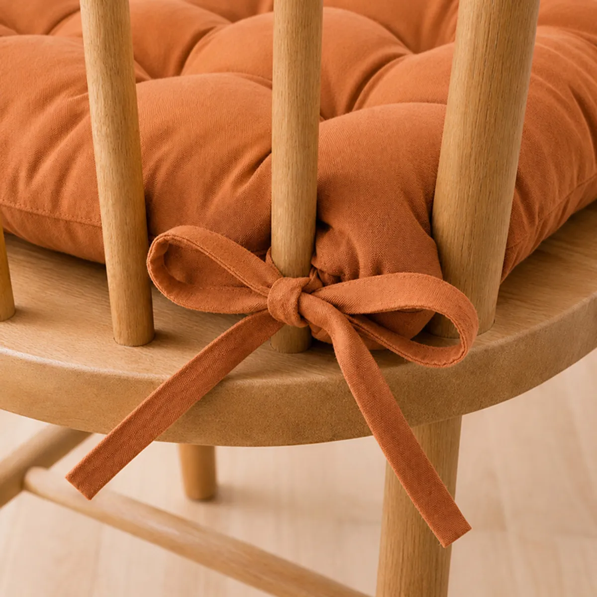 Brown chair pad secured to a wooden chair with fabric ties