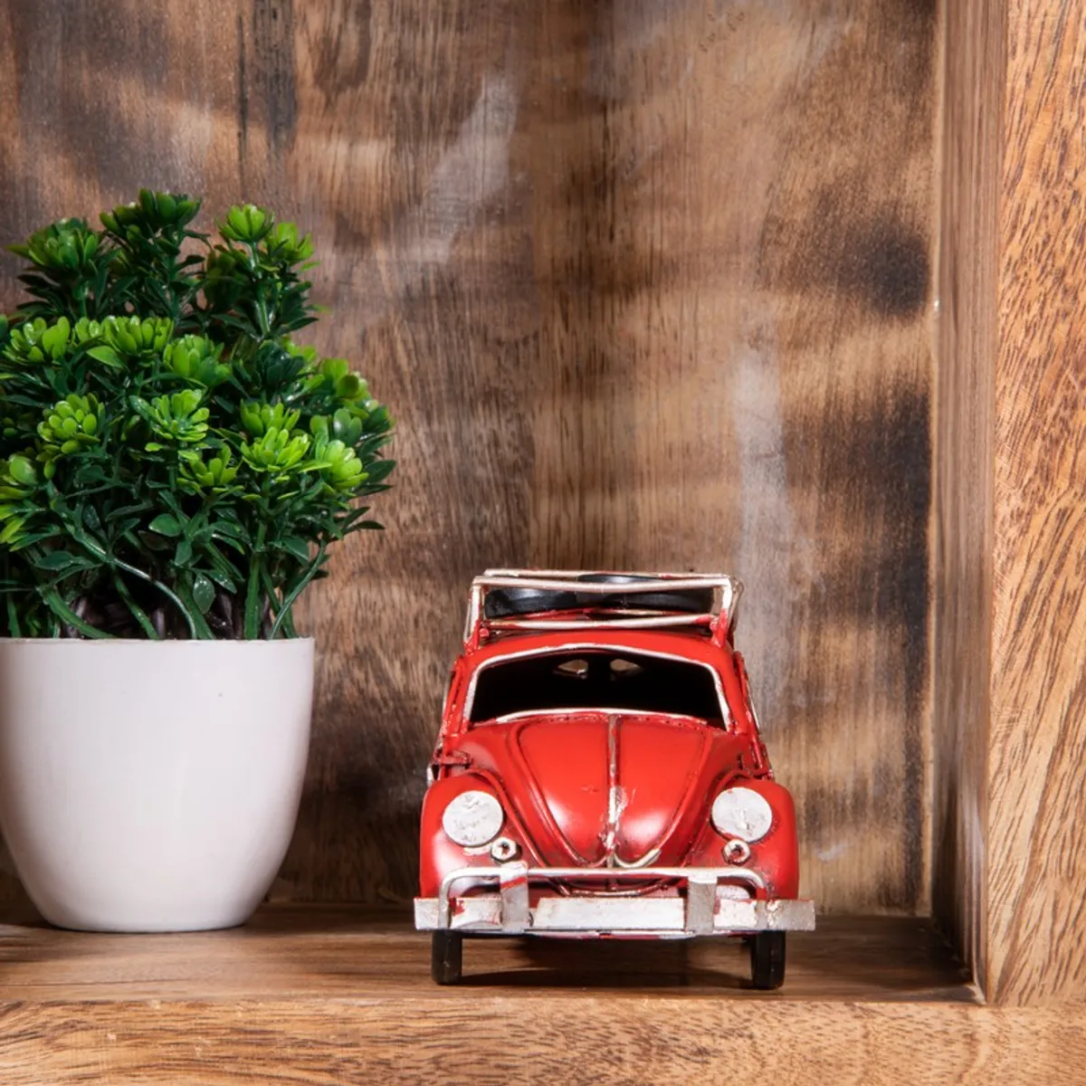 Front view of red vintage car showpiece on wooden shelf