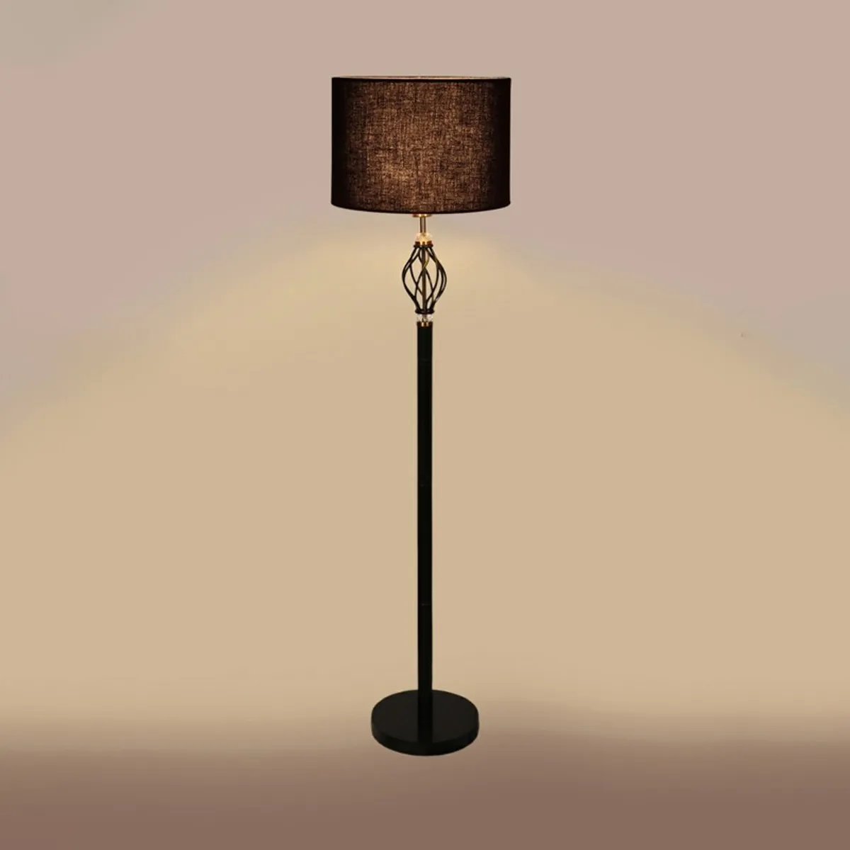 Black floor lamp switched on against a plain warm beige background