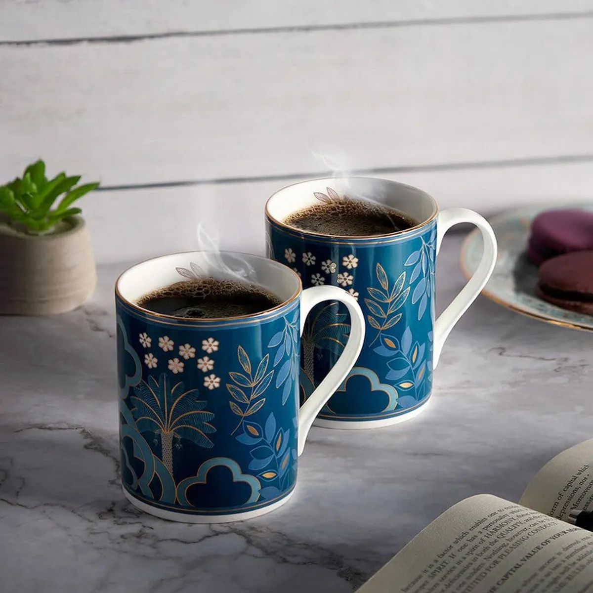 Two matching blue floral mugs with white handles holding hot beverages.