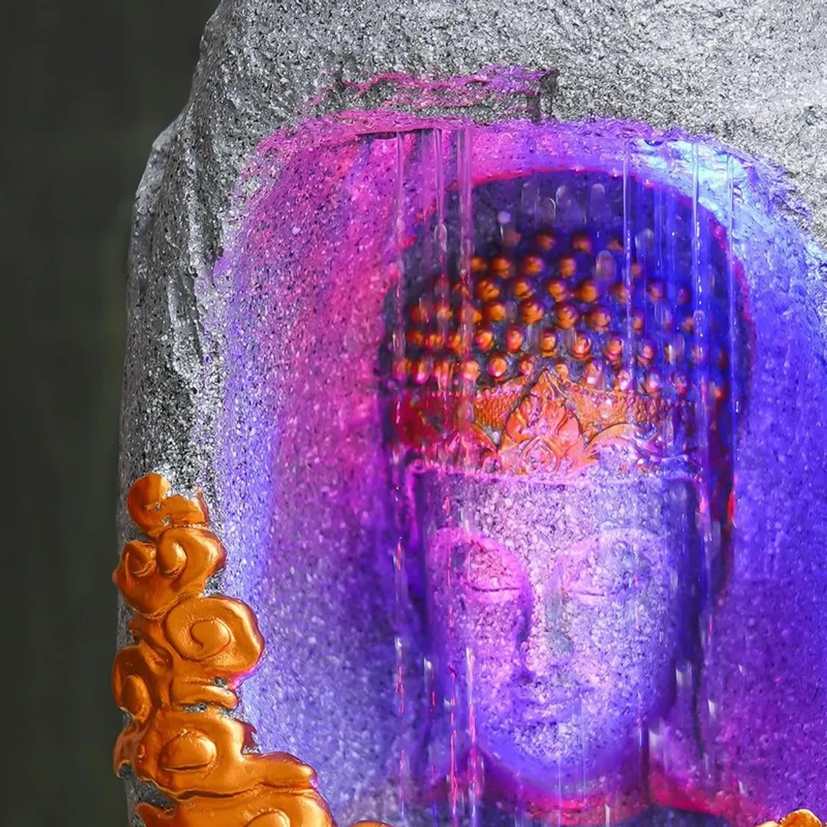 Close-up of Buddha face behind illuminated water flow