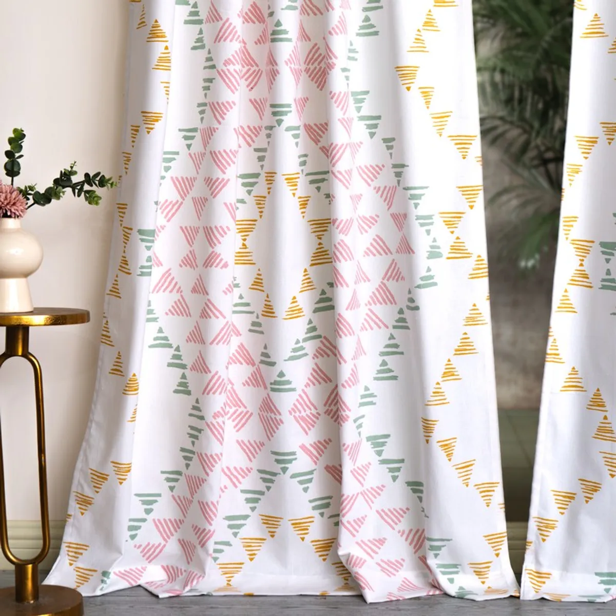 White printed curtain panels styled beside a vase and side table