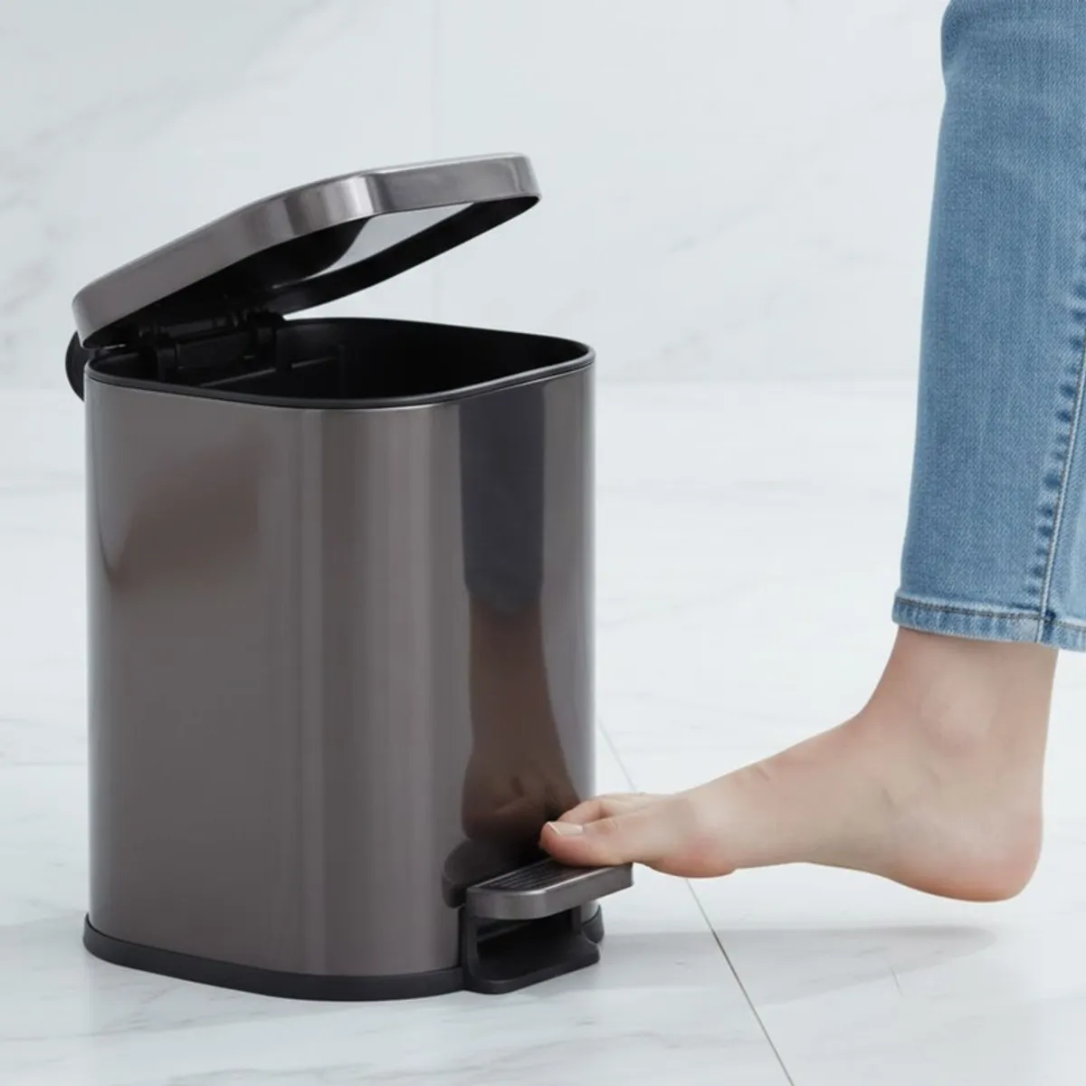 Open black and silver dustbin with foot pedal being pressed