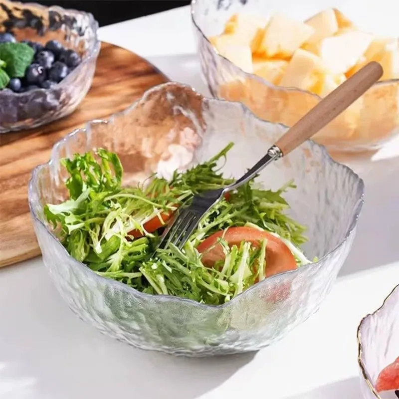 Transparent textured glass bowl filled with green salad and a serving fork