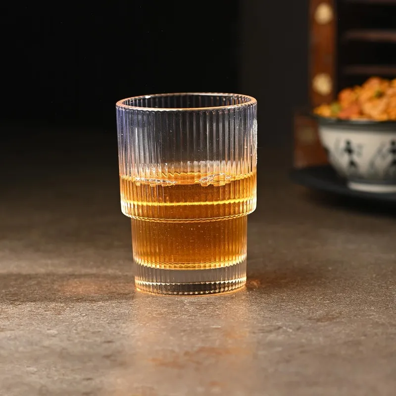 Single clear ribbed cocktail glass filled with amber drink