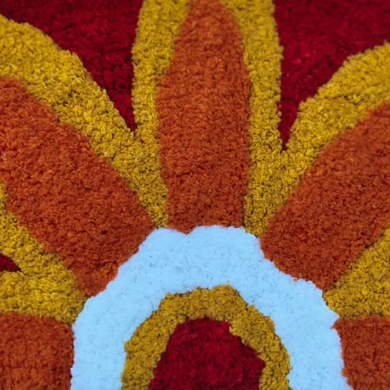 Close-up view of the raised tufted sunflower motif in warm colours